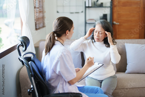 Portrait of a female doctor talking to an elderly patient showing headache.