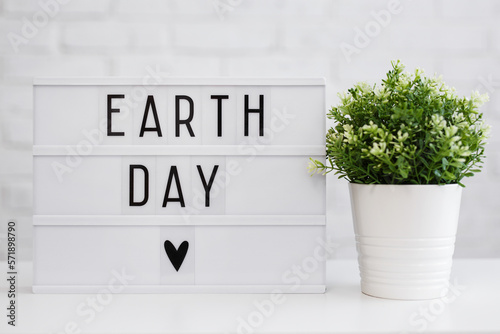 Earth day concept - lightbox with earth day words and potted house plant