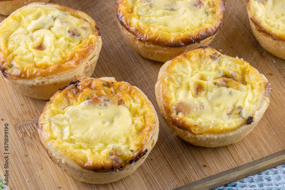 Appetizer quiches homemade on wooden kitchen board close up