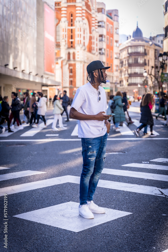 African American young man in the city, portrait of a man with a phone at a zebra crossing