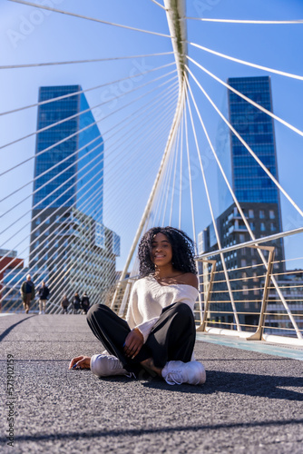 African american young woman in the city, portrait of a young woman sitting laughing on a bridge