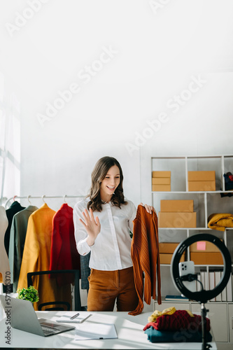 Fashion blogger concept, Young Asian women selling clothes on video streaming.Startup small business SME, using smartphone or tablet taking receive and checking.