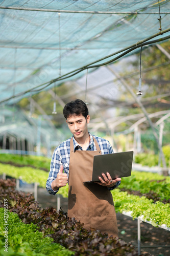 Asian man farmer looking organic vegetables and holding tablet, laptop for checking orders or quality farm