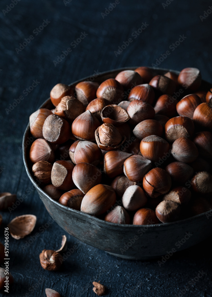 Obraz premium Hazelnut in a metal glass on a wooden background in rustic style. Raw hazelnuts. 