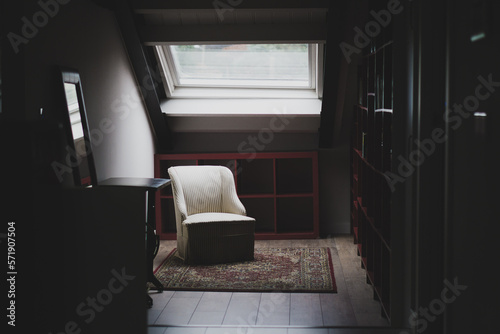 Zona de lectura con un sillón blanco debajo de un ventanal photo