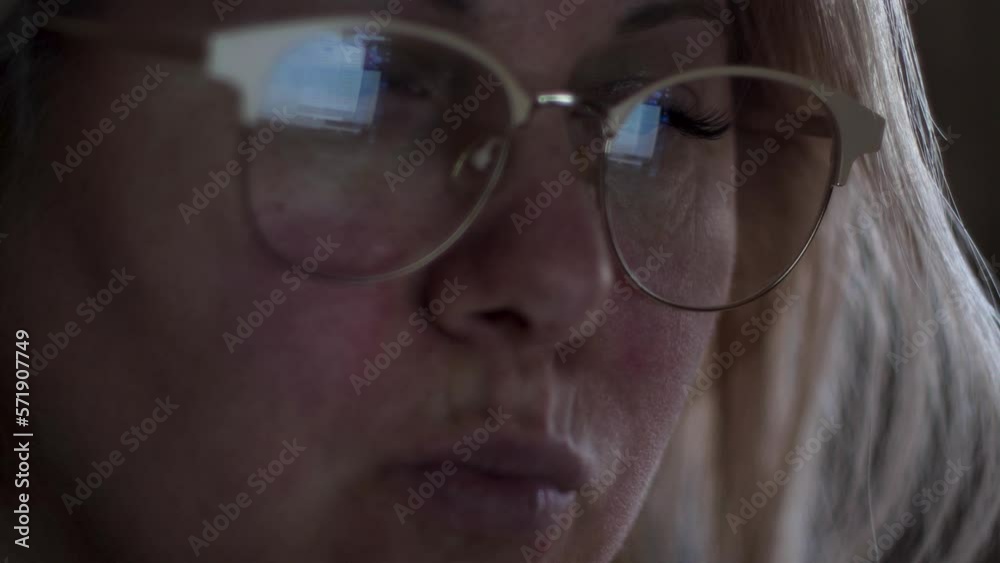 portrait of an attractive focused caucasian blonde woman 30-40 years old working on a computer at home, in a woman's glasses a laptop monitor is reflected. selective focus portrait of an attractive focused caucasian blonde woman 30-40 years old working on a computer at home, in a woman's glasses a laptop monitor is reflected. selective focus