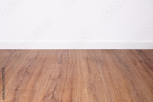 dark oak laminate with white baseboard and white wall as background for design co © MG-Pictures