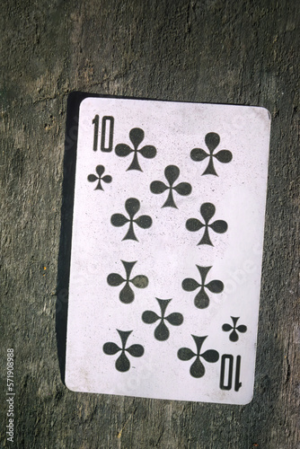 Playing card ten of cross on the background of an old wooden table.