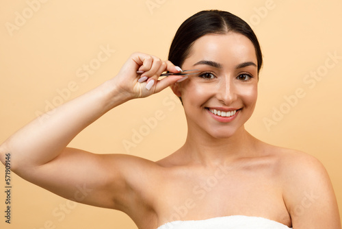 Portrait Of Beautiful Young Indian Woman Plucking Eyebrows With Tweezers