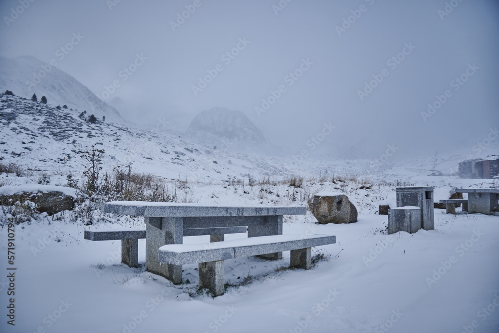 Winter landscape with snow-covered benches and misty mountains in Andorra