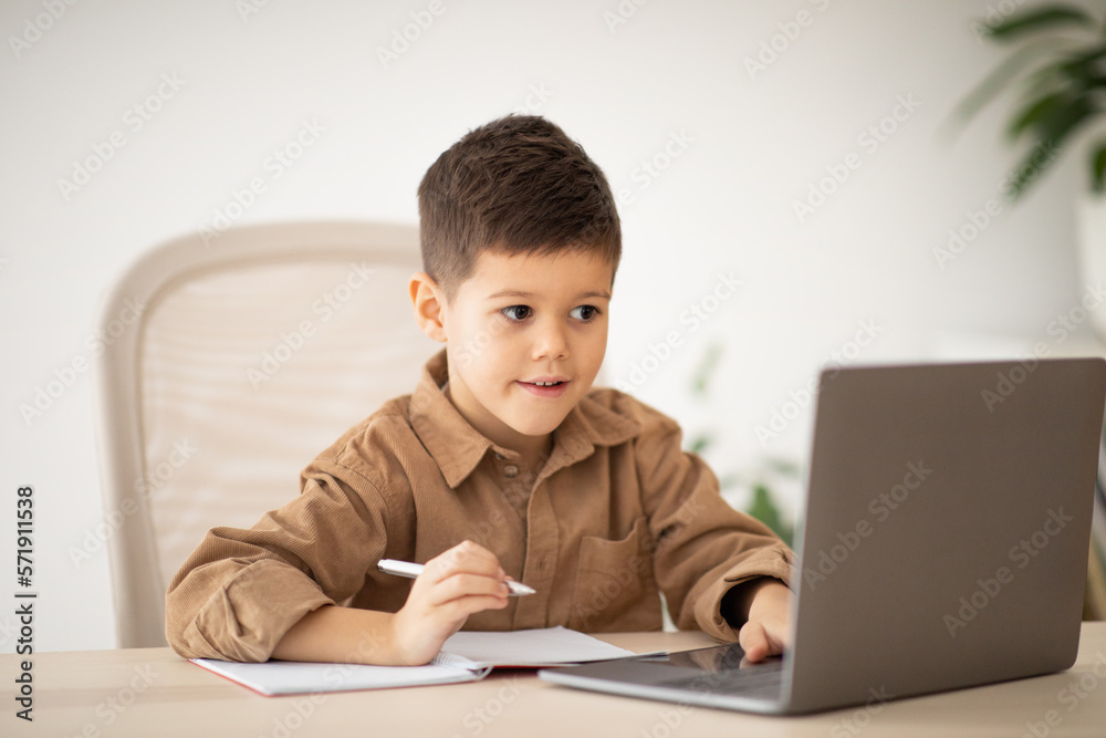 Lesson remote, new normal at home. Happy european small kid has video call with teacher, tutor at table Lesson remote, new normal at home. Happy european small kid has video call with teacher, tutor at table