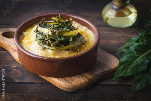 Pugliese recipe   Fave e cicoria:  fava beans or broad beans porridge  with Asparagus chicory, italian dandelion chicory or Catalonian chicory on the wooden  rustic table, tradition poor Bari cuisine  photo