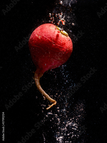 red radish falling into water with splash