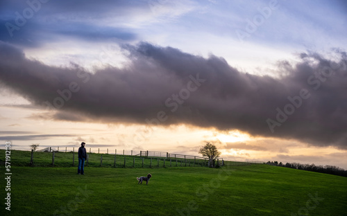 A woman out walking her dog on a cold winters evening as the sunsets over the English countryside