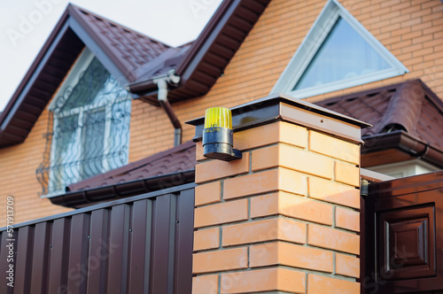 Gate opening sensor for a car on a brick post. Entrance to the yard of a private house © Andrii_Abriutin