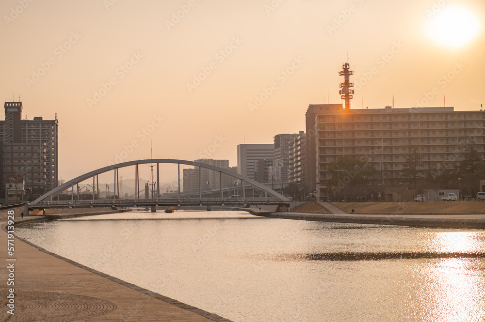 Obraz premium 紫川に架かる鉄の箸と街並みの夕暮れ