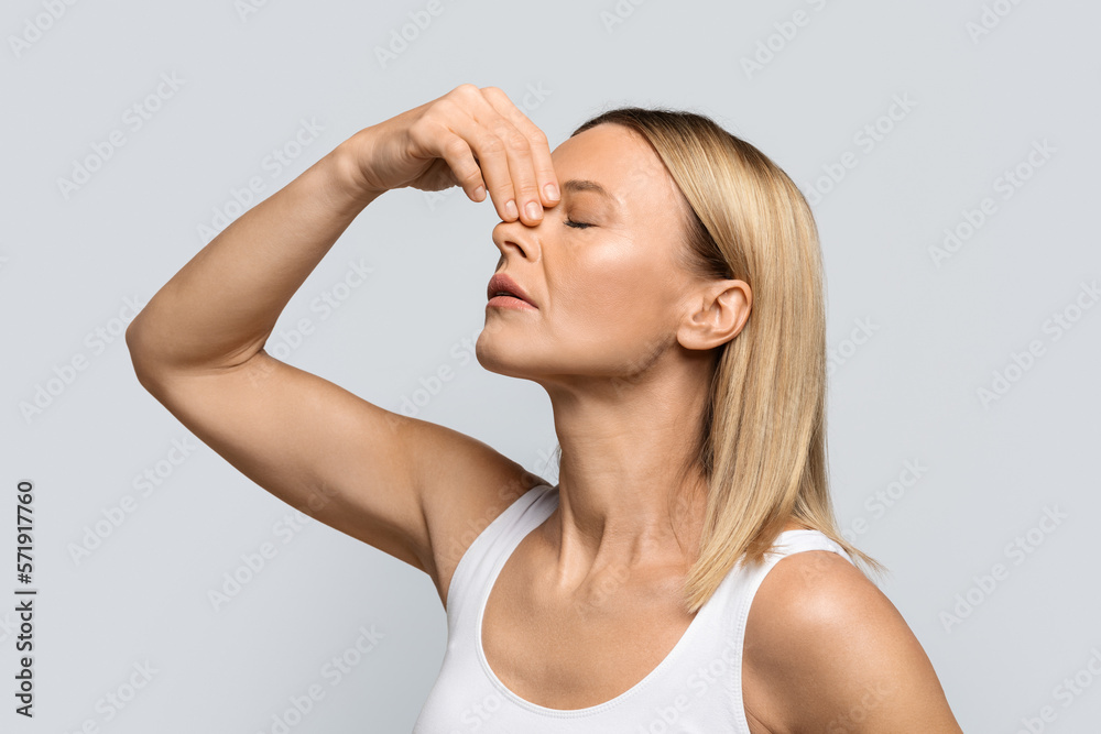 Blonde woman touching nose, suffering from bleeding Blonde woman touching nose, suffering from bleeding
