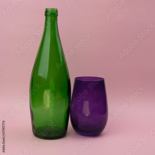 Colorful green glass bottle and empty purplr glass background photo
