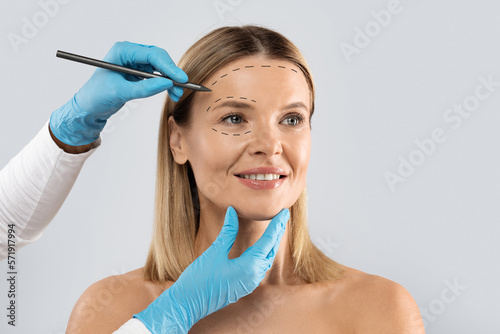 Beautitian drawing contours on woman face before beauty treatment