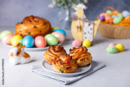 Craffin mini (Cruffin) with raisins and candied fruits. Traditional Easter Bread Kulich. In the background is a large cruffin and painted eggs on a gray background. Easter Holiday. Selective focus.