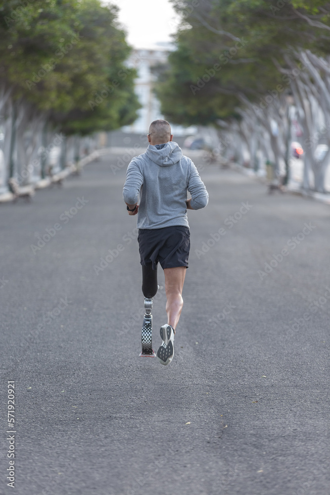 Anonymous amputee jogging on asphalt path