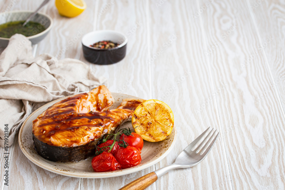 Grilled salmon steak glazed with teriyaki sauce, tomatoes and lemon Grilled salmon steak glazed with teriyaki sauce, tomatoes and lemon