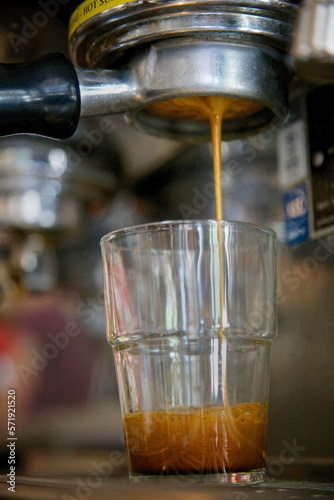Close-up of espresso dripping from a bottomless portafilter into glass cup