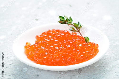 Caviar. Red caviar in a bowl. Macro photo. On a gray concrete photo.