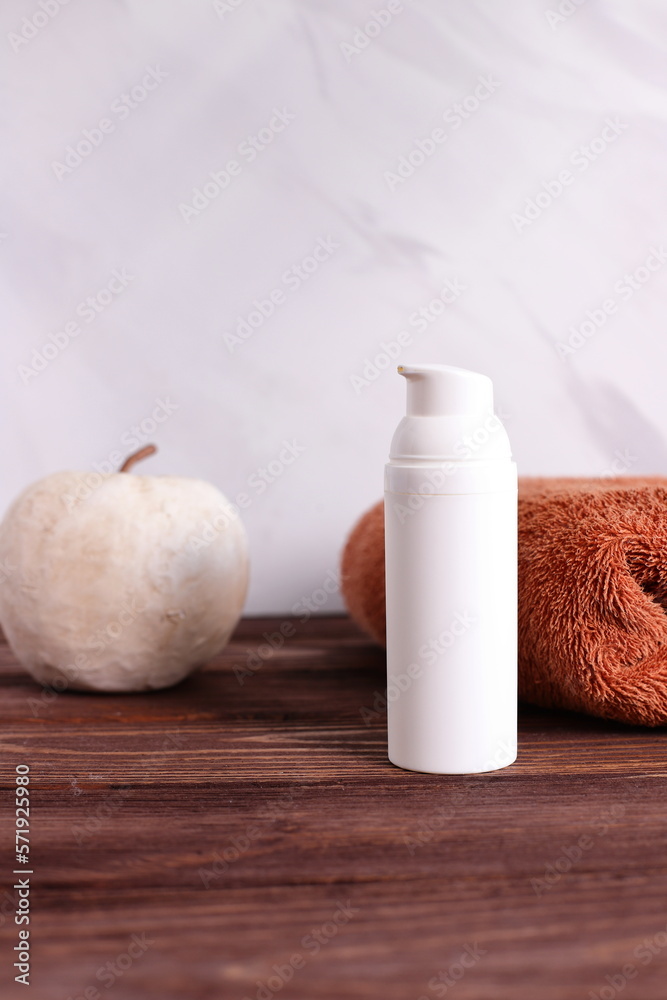 White cosmetic bottle with towel on wooden table, bath staging White cosmetic bottle with towel on wooden table, bath staging
