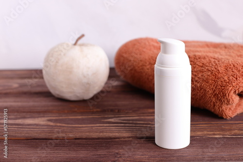 White cosmetic bottle with towel on wooden table  bath staging
