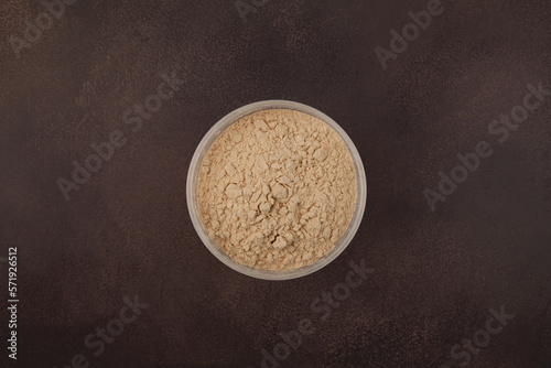 Soy Protein isolate in transparent plastic box, top view. Pure powder isolated from soybean used in food industry. Defatted Soya flour promotes the growth of muscle tissue in athletes photo
