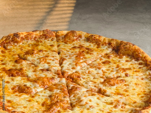 New York style pizza with melted cheese and base tomato sauce close-up.