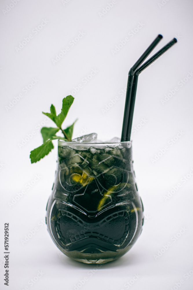 Cóctel de bebida con alcohol de color negro en un vaso decorado con  hierbabuena, lima, pajitas negras e hielo picado con el fondo blanco Stock  Photo | Adobe Stock