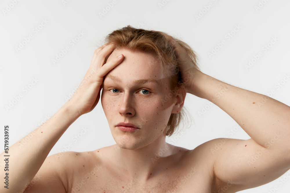 Self-care. Portrait of young redhead man posing shirtless, doing hairstyle after shower over grey studio background. Concept of men's health, body and skin care, hygiene and male cosmetology Self-care. Portrait of young redhead man posing shirtless, doing hairstyle after shower over grey studio background. Concept of men's health, body and skin care, hygiene and male cosmetology