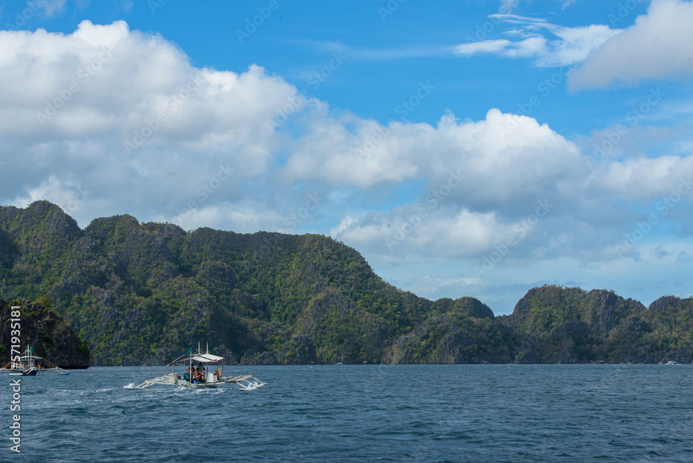 Boat in a tropical country. This photo captures the essence of the Philippines, with a traditional wooden boat bobbing on crystal-clear turquoise waters, surrounded by lush green tropical foliage. 