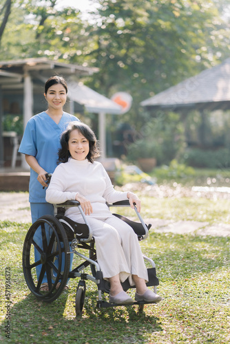 Photo of positive doctor and patient on wheelchair outdoor.