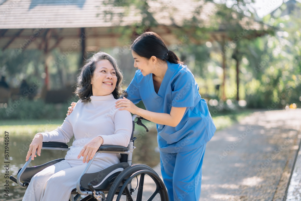 Happy patient is holding caregiver for a hand while spending time together outdoor.
