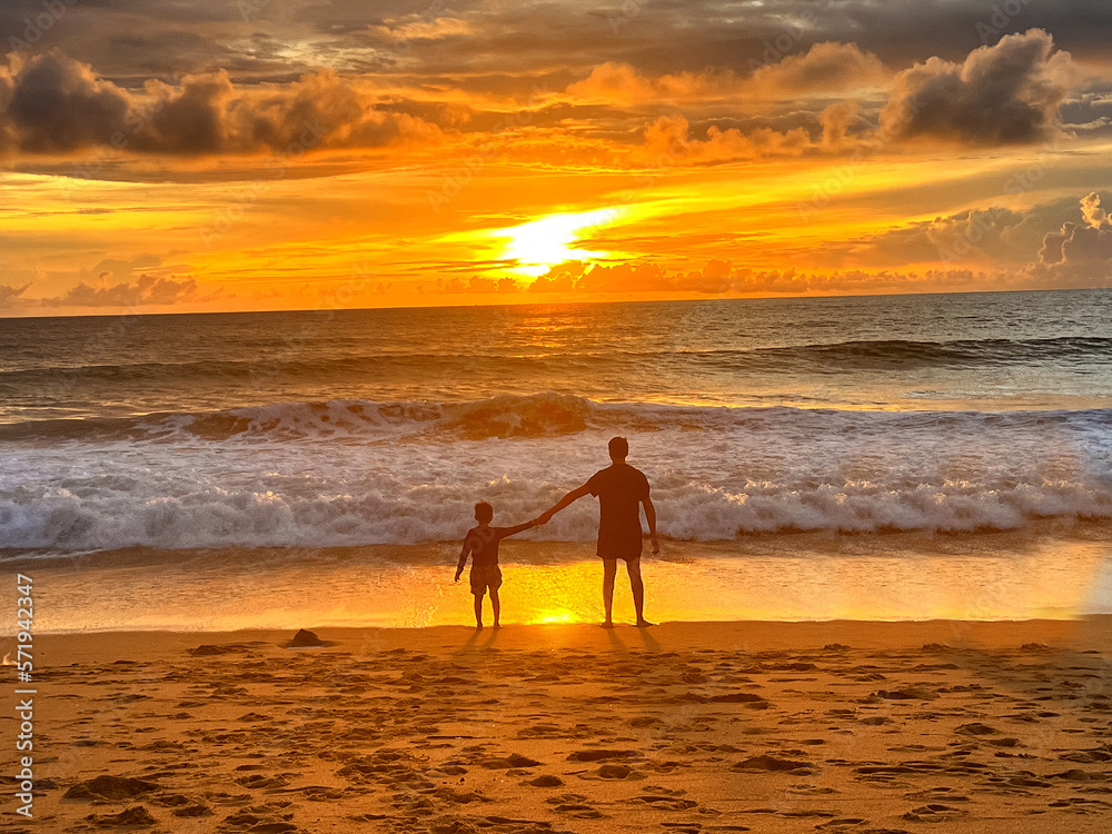 Fototapeta premium Father and son sitting on the beach in the evening