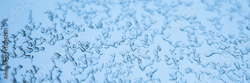 Abstract blue winter background. Texture of frozen water drops, ice surface on the window. Selective focus, web banner