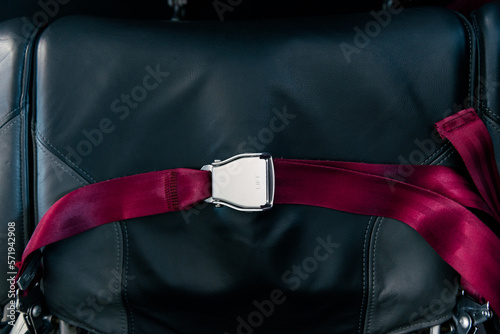 Red seat belt in airplane on black seat. Locked. Safety, prevention accident.