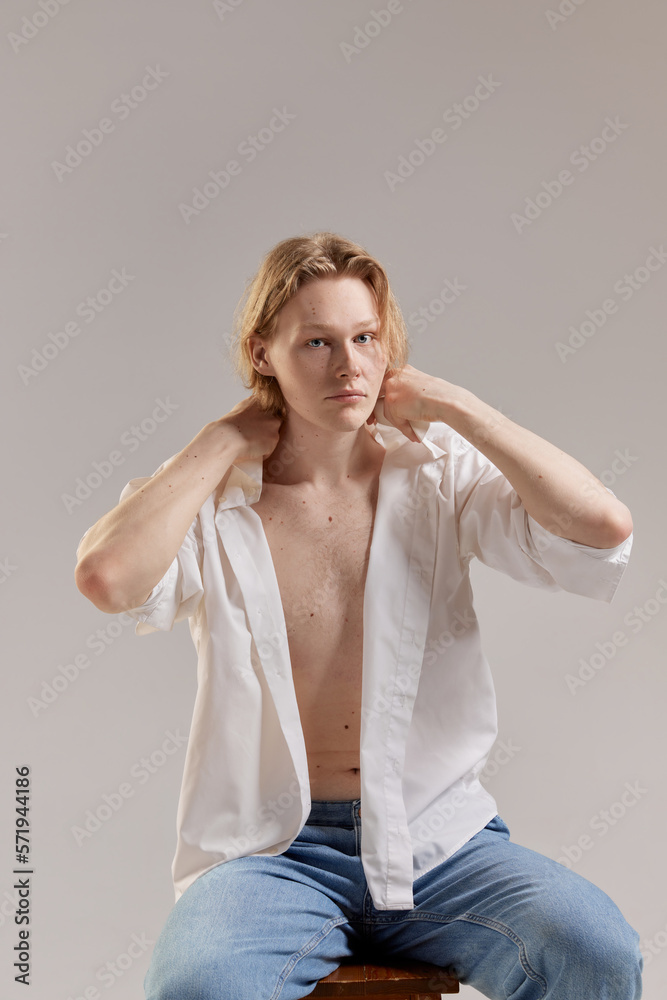 Male fashion and casual style. Portrait of young redhead man posing in white shirt and jeans over grey studio background. Concept of men's health, body and skin care, hygiene and male cosmetology Male fashion and casual style. Portrait of young redhead man posing in white shirt and jeans over grey studio background. Concept of men's health, body and skin care, hygiene and male cosmetology