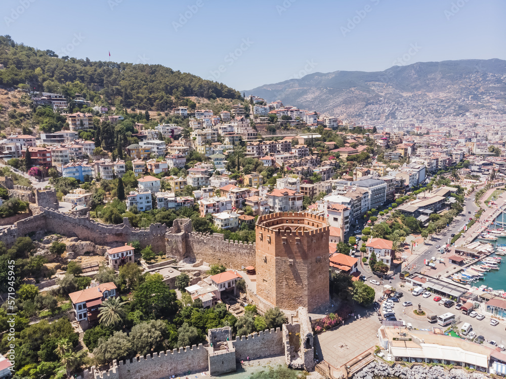 Low-rise buildings of the city of Alanya on a hillside and ancient buildings, on the coast of the sea on a sunny summer day