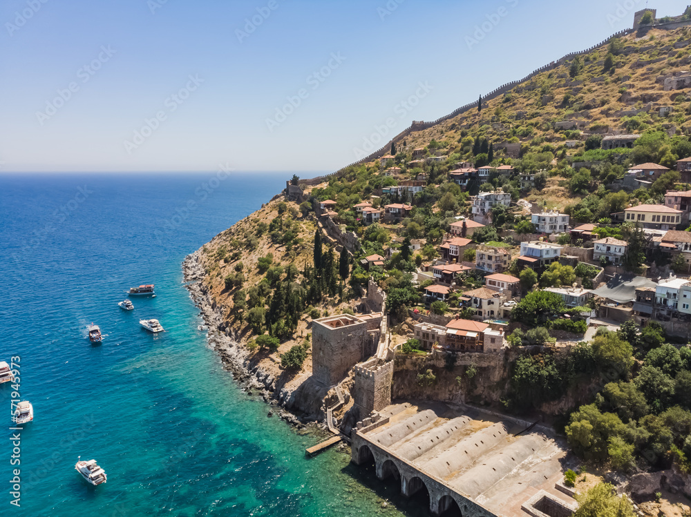 Low-rise buildings of the city of Alanya on a hillside and ancient buildings, on the coast of the sea on a sunny summer day
