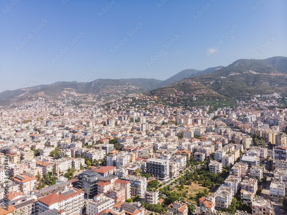 Top view of the tourist city of Alanya in Turkey, low-rise buildings of the city from above against the backdrop of mountains, on a sunny summer day