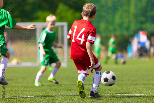 School children in soccer game. Football match for school kids. Young soccer player kicking ball towards goal. Children compete in soccer match