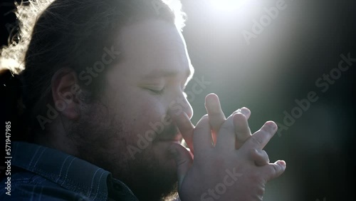 One young chubby man in prayer outdoors in sunlight with fare. Spiritual believer having FAITH praying outdoors in contemplation