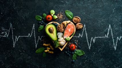 Food banner. Healthy foods low in carbohydrates. Food for heart health: salmon, avocados, blueberries, broccoli, nuts and mushrooms. On a black stone background. Top view.