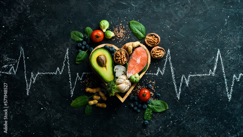 Food banner. Healthy foods low in carbohydrates. Food for heart health: salmon, avocados, blueberries, broccoli, nuts and mushrooms. On a black stone background. Top view.