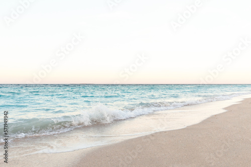 Sunny beach with a turquoise ocean in the background. Sea waves near the tropical coast on a sunny day. Cruise. Landscape of a summer sea beach with white sand.