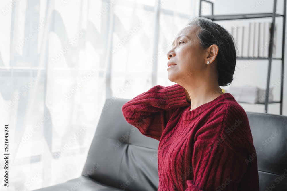 Elderly asian housewife woman sitting on sofa. neck pain